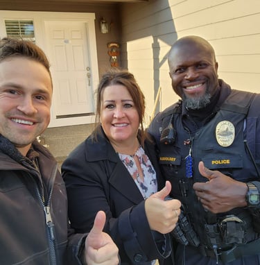 Alex standing with home owners next to their home. A happy husband and wife.
