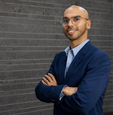 a man abdala bermudez in a suit and tie standing in front of a brick wall