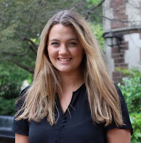 a headshot of a woman with long hair in front of a building