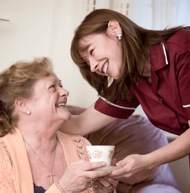 Picture of an AMG Nursing employee/nurse providing a cup of tea to a patient in her home