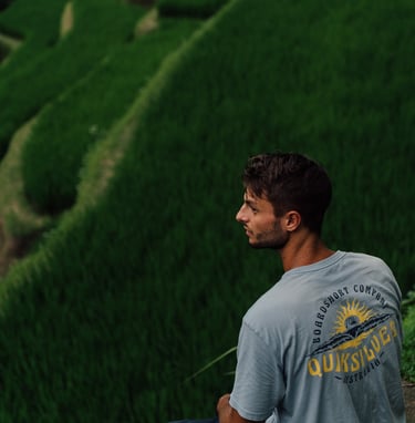 a man sitting on a ledge looking out over a rice field