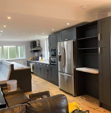 a modern kitchen with a refrigerator, anthracite grey cabinets and seating