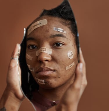 A young woman with acne and skin positive affirmations on her face looking in a broken mirror.