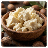 Chunks of raw shea butter in a wooden bowl surrounded by whole shea nuts.