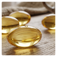 Golden vitamin B oil softgel capsules on a wooden surface for health supplements.