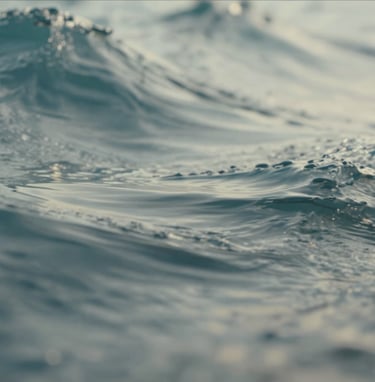 An abstract close-up of moving water or fabric, suggesting motion for a GIF or video still. The colors are a blend of soft blue-grey and muted teal with bright off-white highlights, captured with a professional, sharp lens.