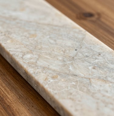 Macro photography of premium interior materials in a South American / Brazilian style, showcasing the texture of polished light quartzite and warm wood. Professional studio lighting emphasizes the refined craftsmanship and off-white and greige color palette.