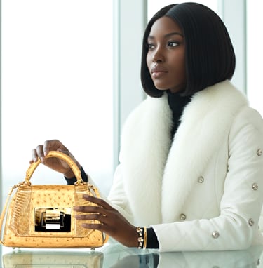 Elegant woman in white fur collar jacket holding a luxury gold ostrich leather handbag.