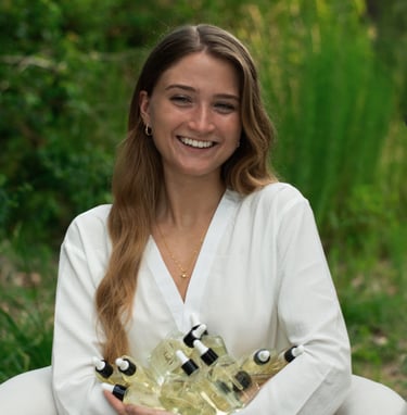 Smiling woman holding a bundle of natural glass dropper bottles for organic skincare products.