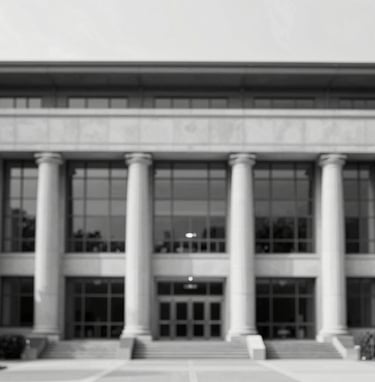 A black and white photograph of a modern library facade in the USA, emphasizing symmetry and professional academic structure, with high contrast lighting.