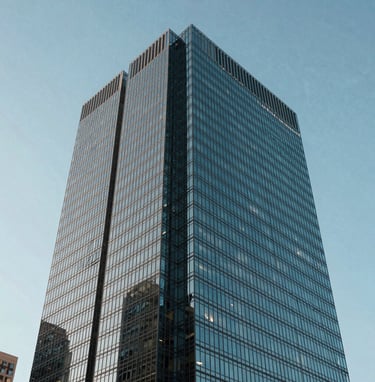 Sharp photography of a modern glass skyscraper corner against a clear pale blue sky, North American / US city, emphasizing geometric precision and sophisticated engineering.