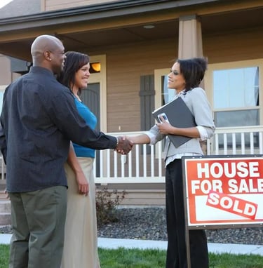 A man and woman shaking hands in front of a house