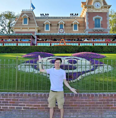 Travel Agent Andrew stands in front of the Main Street Train Station at the entrance to Disneyland.
