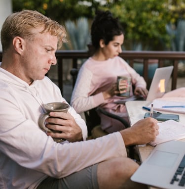a man and woman sitting at a table with laptops