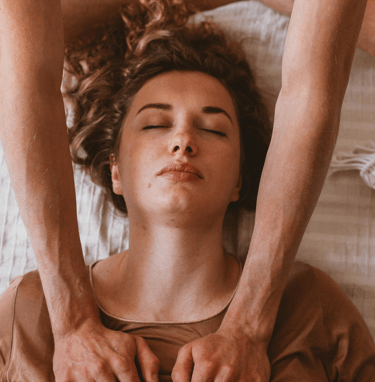 Practitioner performing gentle energy work on a woman’s chest and shoulders as she relaxes