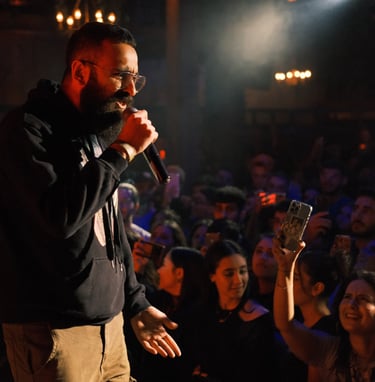 a man in a black jacket and sunglasses is holding a microphone in a concert rap performance