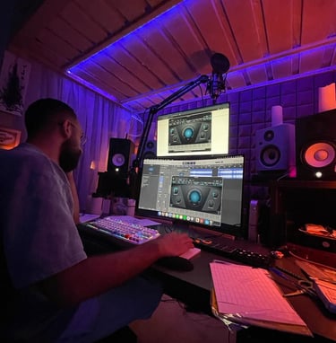 a man sitting at a desk with a laptop computer and a microphone in a studio making music in lebanon