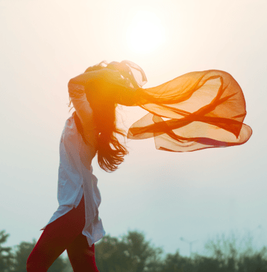 woman with flowing orange scarf in wind and sunlight