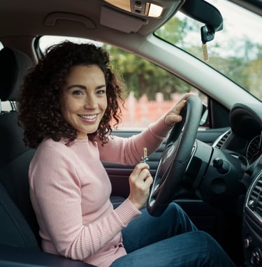 a woman in a pink sweater is sitting in a car hold a key in hand after locksmith programmed it