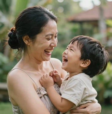 An intimate, close-up shot of a mother and child laughing in a Bali garden. Soft, natural morning light, warm skin tones, and subtle hints of #F8F5EF in the clothing. Elegant and authentic composition.