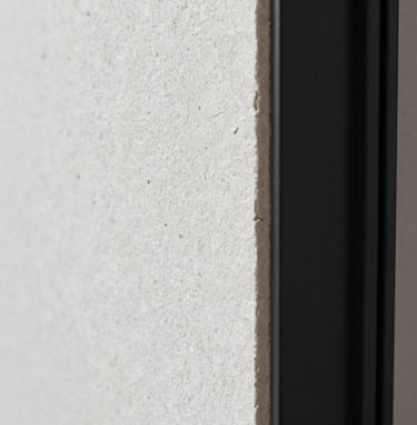 Macro photography of refined construction finishes, focusing on the texture of a polished white stone wall meeting a matte black metal frame, modern and sophisticated aesthetic, soft studio lighting.