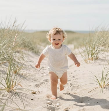 A candid photograph of a toddler running through a light almond colored beach grass field in West Michigan. High-key lighting, soft focus, capturing pure joy and natural beauty. Warm sand and pearl white tones.