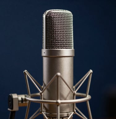A close-up photograph of a premium condenser microphone in a professional studio setting in Southern Europe. The lighting is cinematic and focused, highlighting the metallic textures against a dark navy blue background. Professional excellence and sophistication.