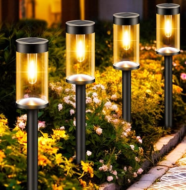 Four glowing solar garden lights illuminating a flower bed path at night with warm yellow light.