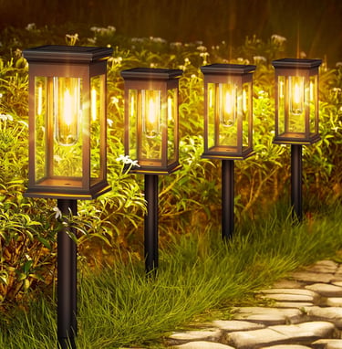 Set of four warm LED solar pathway lights illuminating a stone garden walkway at night.