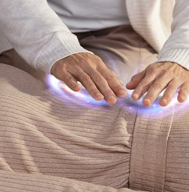 Person's hands hovering over another person, emitting a glowing light, during energy healing.