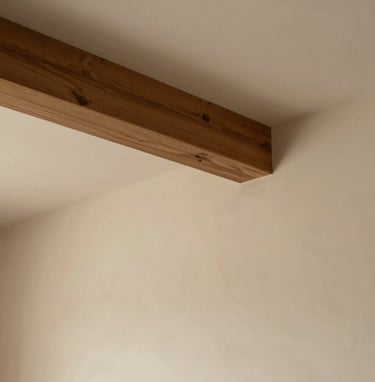 An interior architectural shot focusing on a single wooden beam and a plastered wall. The lighting is diffuse and warm (#7C4E3A), creating a philosophical and quiet atmosphere. Clean lines, ample whitespace.