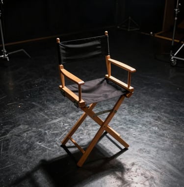 A high-angle shot of a classic director's chair positioned on a North American / US studio soundstage. The lighting is low-key with a single spotlight creating sharp contrast against the dark charcoal floor, reflecting a dramatic cinematic mood.