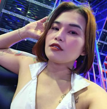 Lady sat on a sofa with on hand on her head and wearing a white sleeveless top 