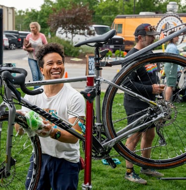 Smiling young man washing a bike with a sponge