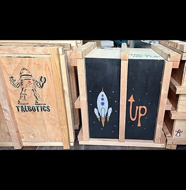 Shipping crate for Talbotics sculpture with image of rocketship drawn on it.