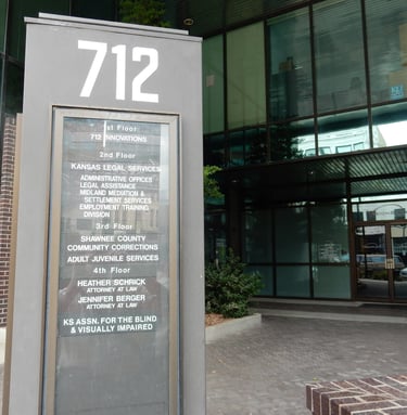 "A tall gray outdoor directory sign displaying '712' at the top, located in front of the KABVI offic
