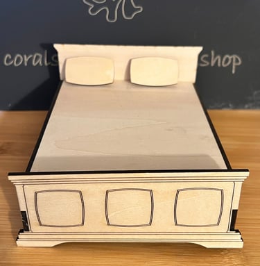 Small wooden miniature bed with headboard and pillows. 