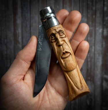 Custom hand-carved Opinel folding knife with a face sculpture on the wooden handle.