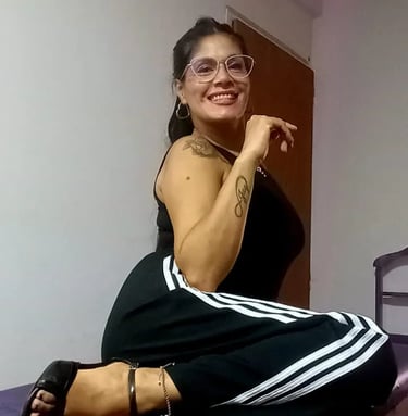 Tama masajes sensuales Palermo, sentada con outfit deportivo y anteojos en su espacio de relax.