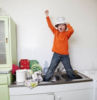 a young boy standing in joy in a kitchen sink