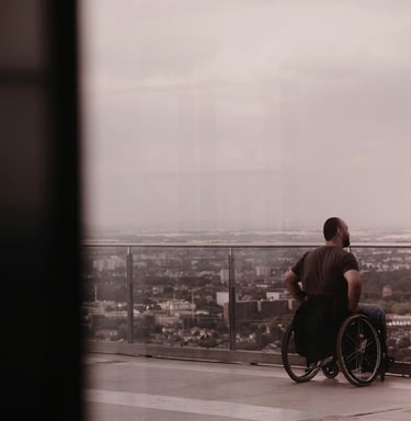 Mann mit Rollstuhl ist auf einem Hotel-Balkon und schaut über eine Stadt