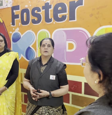Preschool teachers at Foster Kids play school standing in a classroom with educational wall charts.