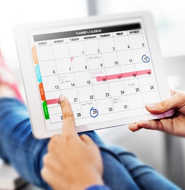 a person holding a tablet with a calendar on it