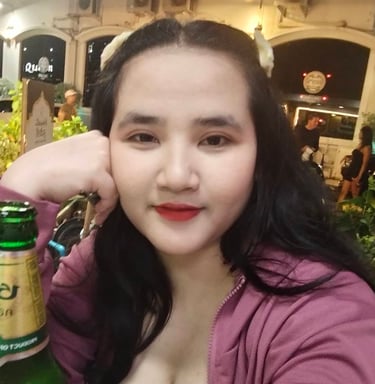 Lady seated with fisted hand on cheek with a bottle of beer in front of her