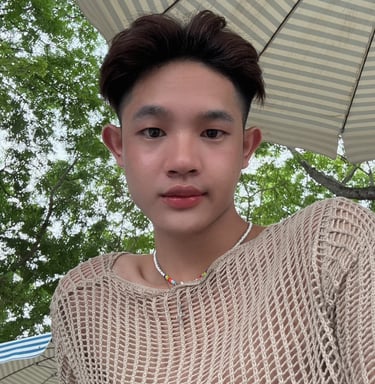 A man wearing a mesh top with large umbrella in the background