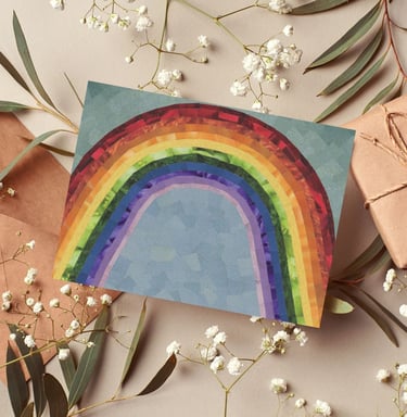 Handmade rainbow greeting card surrounded by baby's breath flowers and kraft paper gifts.