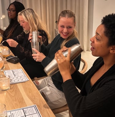 Clients smiling while shaking cocktail tins during a mixology class event.