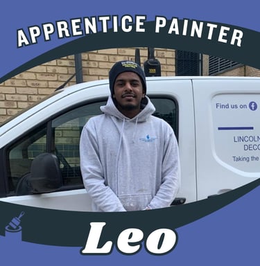 Portrait of Leo, an apprentice painter, standing and smiling in front of a van.