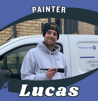 Portrait of Lucas, an LPAD painter, holding a paintbrush whilst smiling, in front of a van..