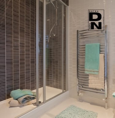 Ducha con mampara de cristal y azulejos decorativos oscuros, estilo elegante y moderno en baño reformado por Dutxa Nova en Va